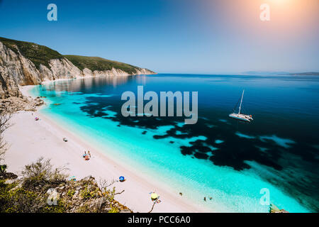 Fteri Strand, Insel Kefalonia Kefalonia, Griechenland. Weißen Katamaran Yacht in klaren, blauen Meer Wasser. Touristen am Sandstrand der Lagune. Stockfoto