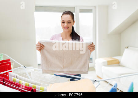 Frau, die Handtücher vom Wäscheständer zu Hause Stockfoto