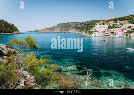 Türkis transparent Lagoon von grünen Pinien umgeben. Assos Dorf, Kefalonia, Griechenland. Blauen Tiefen Muster auf Mittelmeer unten. Stockfoto