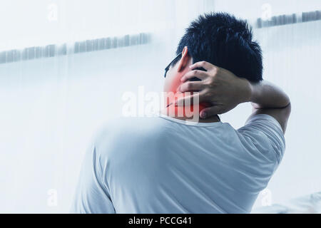 Asiatischer mann Hals Schmerzen nach dem Aufwachen am Morgen auf dem Bett im Schlafzimmer. Farbton Stockfoto