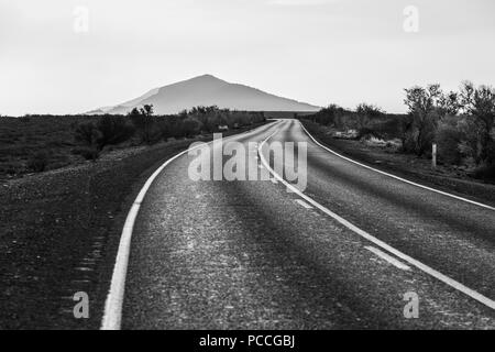 Kurvenreiche Straße führt zu einem malerischen Berg in Schwarz und Weiß Stockfoto