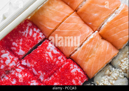 bunten Rollen und Sushi-Reis, Kaviar und Lachs, liegen auf dem Tisch im Hintergrund Stockfoto