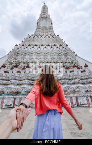 Porträt der schönen Asiatin führt Ihr Partner von Hand zu den berühmten Wat Arun. Wat Arun ist ein buddhistischer Tempel in Bangkok, Thailand. Stockfoto