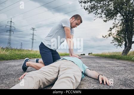 Reanimation auf der Landstraße gegen dramatische Himmel. Themen Rettung, Hilfe und Hoffnung. Stockfoto