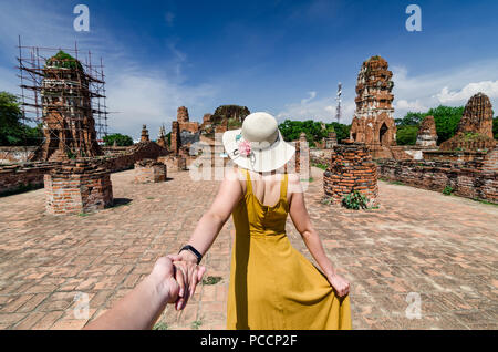 Porträt der schönen Asiatin führt Ihr Partner von Hand zu den berühmten Wat Mahathat. Der Wat ist ein buddhistischer Tempel in Ayutthaya, Thailand. Stockfoto
