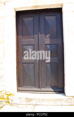 Eine dunkle Holztür auf einen weißen Stein Wand Stockfoto