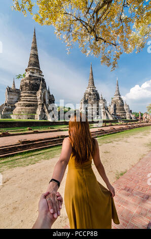 Porträt der schönen Asiatin führt Ihr Partner von Hand zu den berühmten Wat Phra Si Sanphet. Der Wat ist ein buddhistischer Tempel in Ayutthaya, Thailand. Stockfoto