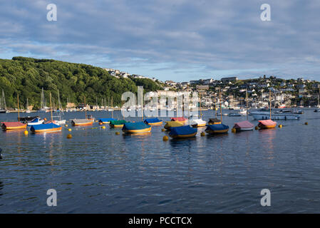 Am frühen Abend Licht auf eine Gruppe von Jollen in Fowey Hafen. Das Dorf Polruan im Hintergrund. Fowey, Cornwall, England, Großbritannien. Stockfoto