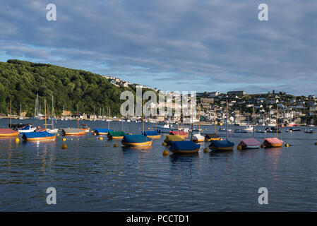 Am frühen Abend Licht auf eine Gruppe von Jollen in Fowey Hafen. Das Dorf Polruan im Hintergrund. Fowey, Cornwall, England, Großbritannien. Stockfoto