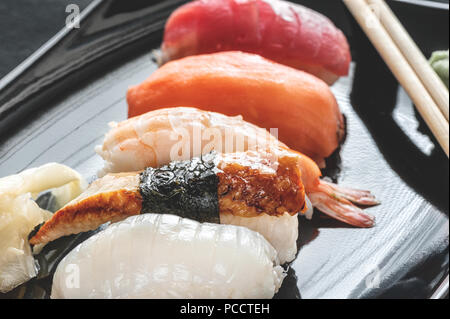 bunten Rollen und Sushi-Reis, Kaviar und Lachs, liegen auf dem Tisch im Hintergrund Stockfoto