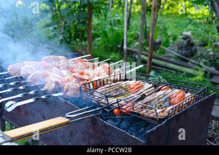 Würstchen mit Gemüse und Shish Kebab sind gegrillt auf Feuer. Kochen Abendessen im Freien. Stockfoto