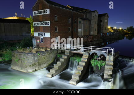 Castleford Stoneground Mühle in der Nacht neben der Millennium Bridge, die sich über den Fluss Aire Stockfoto