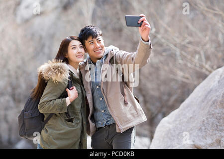 Glückliche junge chinesische Paar unter selfies im Winter Stockfoto