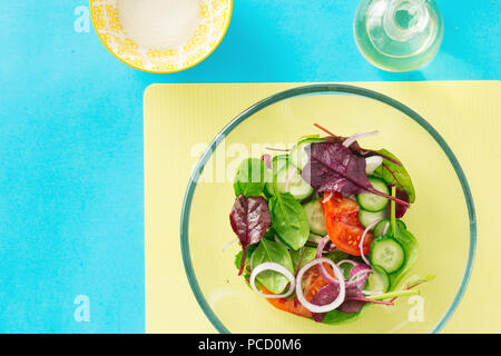 Gesunde Ernährung Konzept. Diät essen. Frische Sommer Salat in Glasschale auf blauem Hintergrund, Ansicht von oben Stockfoto