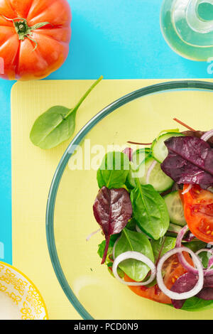 Sommer Salat in Glasschale auf blauem Hintergrund, Ansicht von oben. Gesunde Ernährung Konzept. Ernährung Lebensmittel Stockfoto