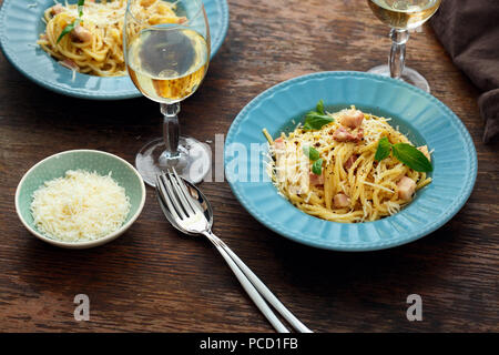 Teller Pasta Carbonara mit Glas Weißwein auf hölzernen Tisch Stockfoto