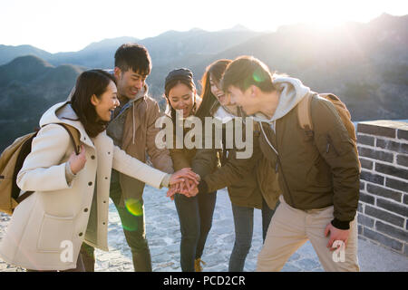 Glückliche junge chinesische Freunde stapeln die Hände auf die Große Mauer Stockfoto