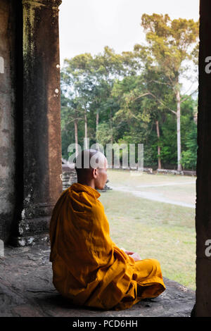 Buddhistischer Mönch sitzt in einem Colonnaded Korridor in einem Tempel in Angkor Wat, UNESCO, Siem Reap, Kambodscha, Indochina, Südostasien, Asien Stockfoto