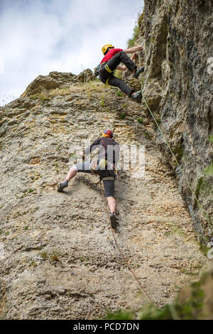 Foto von der Rückseite der klettern junge Sport Männer in Helm auf Rock Stockfoto