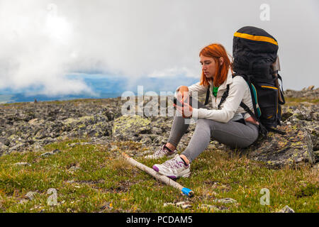 Reisen Lifestyle und Überleben Konzept Sicht nach hinten. Wandern Frauen mit Rucksack sind sehr müde und sitzen auf Rock und Blick auf Phine, genießen die Trekking, Stockfoto