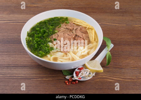 Platte der vietnamesische Nudelsuppe pho bo auf hölzernen Tisch Stockfoto