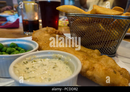 Fisch und Chips in einem Korb mit Garten Erbsen und Sauce Tartar. Stockfoto