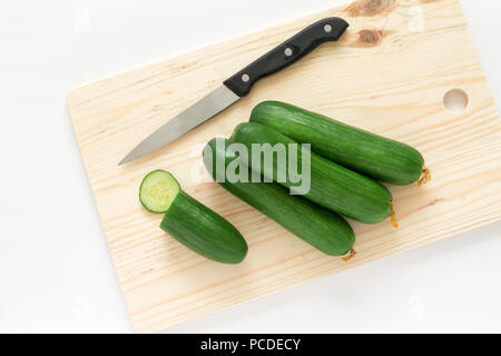 Frische Gurken und Messer auf Holz Schneidebrett Top View Stockfoto