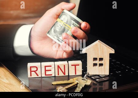 Mieten Sie ein Haus online. Konzept der Immobilien. Modell des Hauses, die Tasten, den Dollar und die Inschrift "Mieten" auf Holzblöcken. Ferienwohnungen. afforda Stockfoto