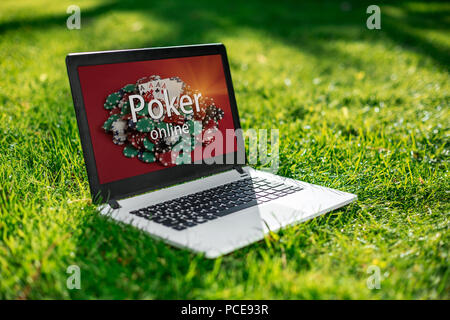 Online Casino, Laptop mit Poker chips Geräts über das grüne Gras. Glücksspiel Stockfoto