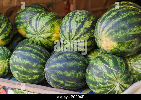 Stapel der frische reife Wassermelonen liegen in Kisten aus Holz, in der Obst- und Gemüseabteilung des Supermarktes. Stockfoto