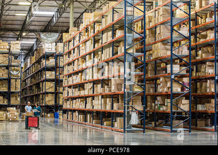 Zwei Mitarbeiter Überprüfung bestand neben Regalen der Boxen in vorübergehenden Lagerung in ein Auslieferungslager. Stockfoto