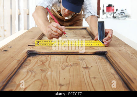 Zimmermann bei der Arbeit Maßnahmen mit dem setsquare und Bleistift auf Holzbrett Hintergrund Stockfoto