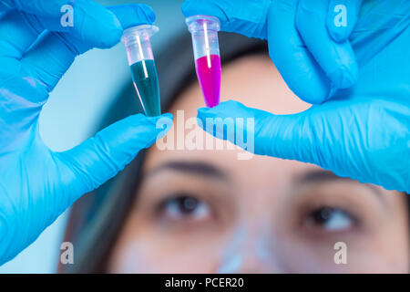 Weibliche medizinischer Arbeiter vergleicht Röhrchen mit biologischen Proben Stockfoto