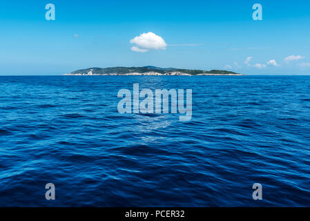 Einzelne kleine Insel in das Blau des Ionischen Meeres mit einer Wolke über es Stockfoto