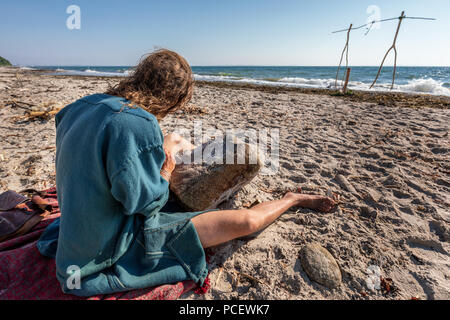 Ein Mann machen Viking Inschriften in einen Stein am Strand während des Moesgaarder strittig, Aarhus, Dänemark Stockfoto