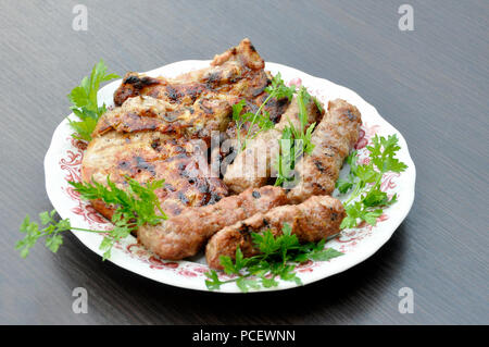 Steak und chevation mit Grill in einer Platte mit Petersilie auf einem grauen Hintergrund Tabelle Stockfoto