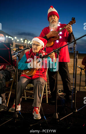 Zwei ältere Musiker in Santa Kostüme spielen gekleidet Du bist mein Sonnenschein' auf ukulelen an eine nächtliche Christmas Festival in Huntington Beach, CA. (Foto von Spencer Grant) Stockfoto