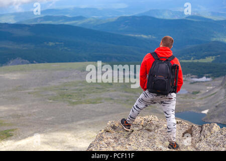 Mann Wanderer genießen Sie den Blick auf den Sonnenuntergang Berg Cliff. Fotograf Reisenden auf hohe mountaint Stilvolle Menschen wandern. Reisen Lifestyle und Überleben con Stockfoto