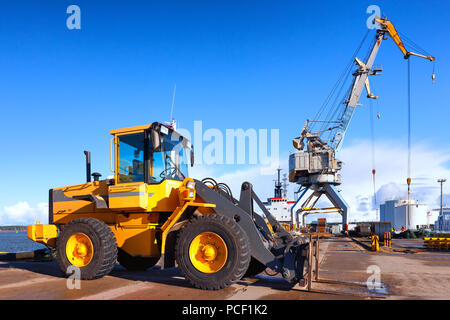 Gelb für Gabelstapler und Kran beim Entladen und Laden der Fracht im Hafen auf dem Hintergrund des blauen Himmels Stockfoto