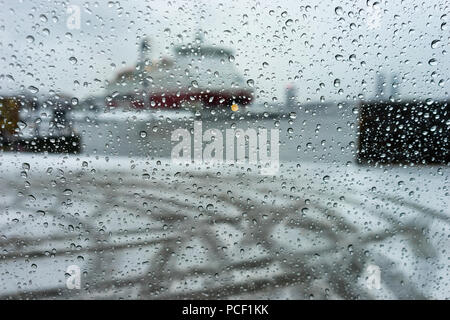 Schiff im Hafen durch die Regentropfen auf dem Fenster des Autos in einen Schneesturm und starker Wind Stockfoto