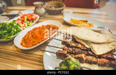 Close up detaillierte Ansicht von gegrillten leckeren türkischen Leber Shish Kebab serviert auf einem weißen Teller mit in Scheiben geschnittenen lavash, Salat und Ayran. Stockfoto
