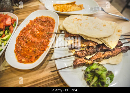 Close up detaillierte Ansicht von gegrillten leckeren türkischen Leber Shish Kebab serviert auf einem weißen Teller mit in Scheiben geschnittenen lavash, Salat und Ayran. Stockfoto