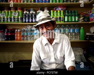 ANTIPOLO CITY, Philippinen - Juli 30, 2018: Ein gut gekleideter stattlicher Mann posiert für die Kamera in den Laden, wo er verkauft verschiedene Getränke und refreshme Stockfoto