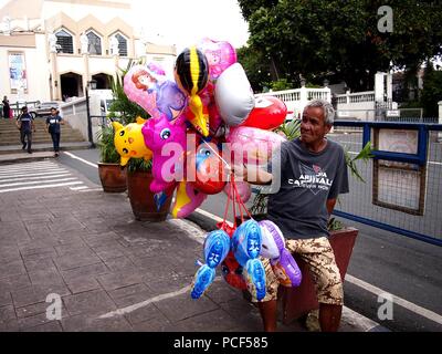 ANTIPOLO CITY, Philippinen - Juli 30, 2018: Ein Mann verkauft sortiert Spielzeug Ballons außerhalb des beliebten Reiseziel Unsere Liebe Frau des Friedens und gute Vo Stockfoto