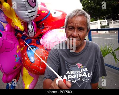 ANTIPOLO CITY, Philippinen - Juli 30, 2018: Ein Mann verkauft sortiert Spielzeug Ballons außerhalb des beliebten Reiseziel Unsere Liebe Frau des Friedens und gute Vo Stockfoto