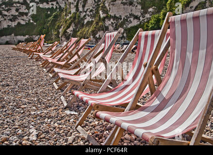 Rote Liegestühle auf einem Kieselstrand Stockfoto
