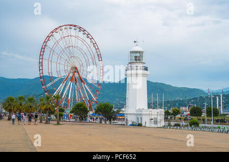 Batumi, Adscharien, Georgien - 16.06.2018: Riesenrad und Batumi Batumi Leuchtturm auf der Strandpromenade im sonnigen Tag. Stockfoto