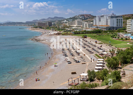 Liegestühle und Sonnenschirme am Strand in Faliraki. Die Insel Rhodos, Dodekanes, Griechenland. Stockfoto