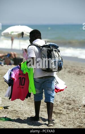 Roquetas de Mar, Almeria, Spanien. 2 Aug, 2018. Die Hitzewelle, schlägt Spanien wird erwartet, 43°C in einigen Teilen des Landes zu überschreiten. Mann verkauf Strand Artikel, t-shirts zu Fuß entlang der Strandpromenade. Foto: Paul Lawrenson/Alamy leben Nachrichten Stockfoto