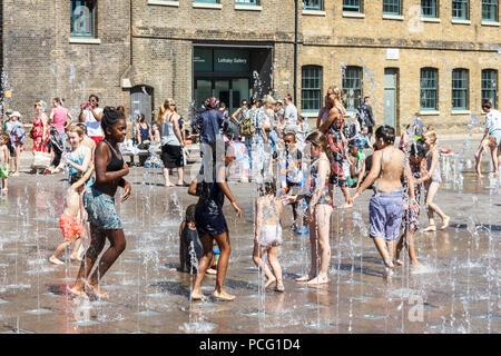 Familien und Kinder kühlen sich in den Brunnen des Granary Square ab, wenn die Temperaturen steigen, King's Cross, London, Großbritannien Stockfoto